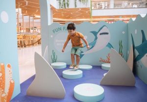 A young boy jumping from circle to circle in a blue ocean display made from Re-Board.