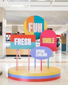 Pop-up display of the words 'Fun, Fresh, Smile, and Into Spring Colour' in a mall. 